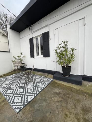 Cette maison blanche dispose d'une terrasse avec une plante. dans l'établissement Chalet, au Blanc-Mesnil