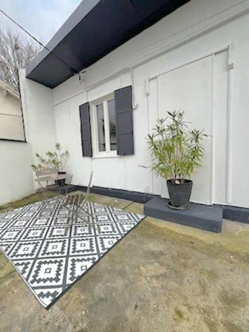 une maison blanche avec une plante en pot à côté dans l'établissement Chalet, au Blanc-Mesnil