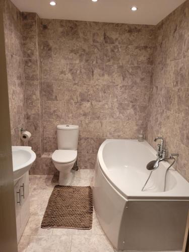 a bathroom with a tub and a toilet and a sink at 75 Park Prewett in Basingstoke