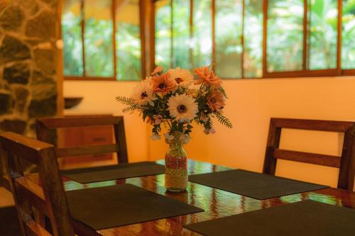 a vase of flowers on a table with two chairs at Finca Las Palmas Ecolodge in Puyo