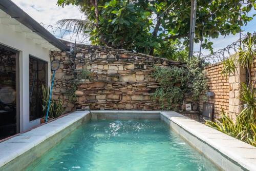 a swimming pool in front of a brick wall at Casa Eva, rústica y cálida familiar in Asuncion