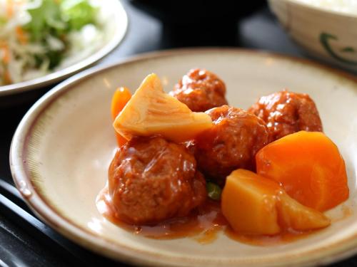 a plate of meatballs and vegetables on a table at Super Hotel Midosujisen Esaka in Suita