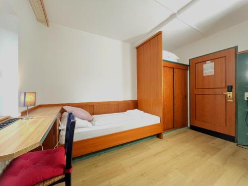 a small bedroom with a bed and a desk at Mountain Hotel & Hostel in Ramsau am Dachstein