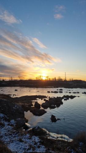 a sunset over a river with rocks in the water at Huset i Stamsund in Rishaugen