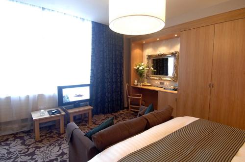 a hotel room with a bed and a couch and a television at The Briar Rose Wetherspoon in Birmingham