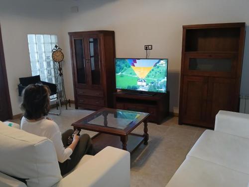 una mujer sentada en una sala jugando un videojuego en Habitación Higuera, en Lumpiaque