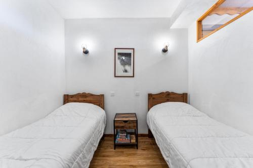 deux lits dans une chambre aux murs blancs dans l'établissement Résidence Les Hauts De Preclaux - Appartement montagnard & chaleureux aux Orres 1800 MAE-3771, aux Orres