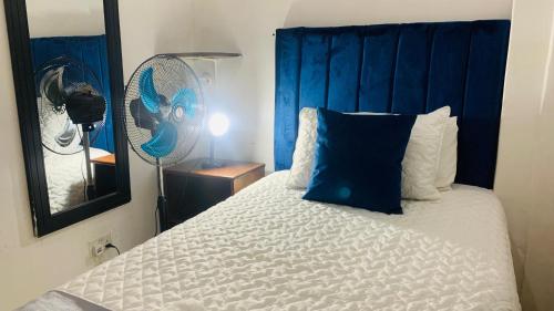 a bedroom with a bed with a blue headboard at Mongi Guest House in Harare