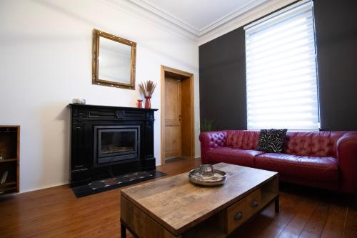 a living room with a red couch and a fireplace at Domaine du Rondia - Chambres d'hôtes et Wellness in Wanze