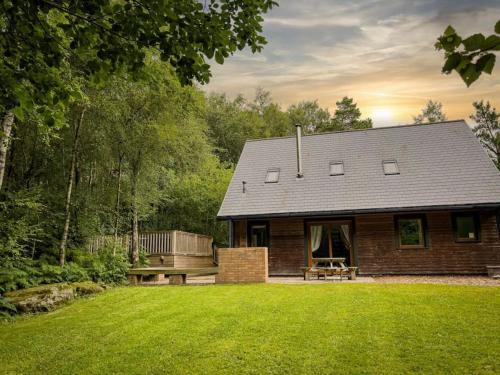 a small brick house with a bench in a yard at Wootton, woodland lodge with hot tub for 8 in Oakamoor