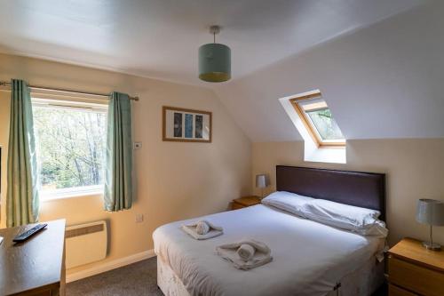 een slaapkamer met een bed met twee handdoeken erop bij Wootton, woodland lodge with hot tub for 8 in Oakamoor