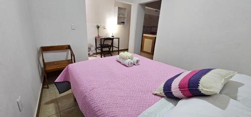 a bedroom with a pink bed with two stuffed animals on it at Depa Púrpura Caracol in San Antonio de la Cal