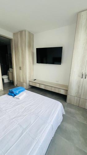 a bedroom with a white bed and a flat screen tv at La posada de Mayté in Santa Marta