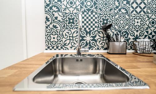 a stainless steel sink in a kitchen with a black and white wallpaper at Valguarnera Studio Apartments in Palermo