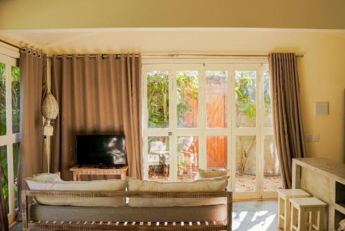 a living room with a couch and a large window at Casa Kokoro in Pipa