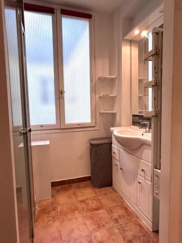 une salle de bain blanche avec un lavabo et une fenêtre dans l'établissement Charmant appartement 45m2 Trocadero, à Paris