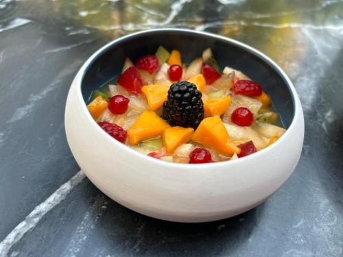 a bowl of cereal with fruit in it on a table at Les Suites Champenoises in Reims