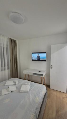 a bedroom with a bed with a desk and a tv on the wall at Bella Vacanza Apartment in Banja Luka
