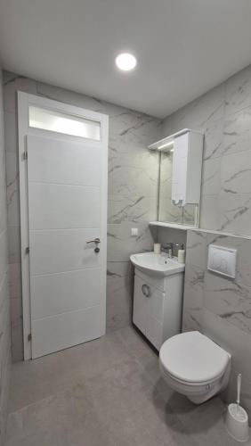 a white bathroom with a toilet and a sink at Bella Vacanza Apartment in Banja Luka