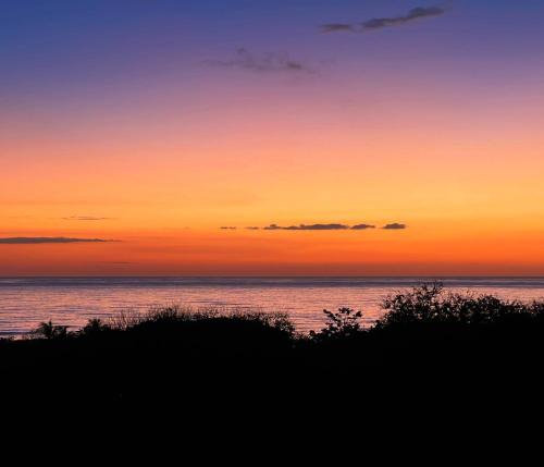 a sunset over the ocean with the horizon at Horizon Hotel & Yoga Center in Santa Teresa Beach