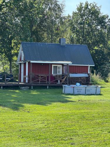 a red house with a black roof in a field at Privaatne talu otse mere ääres in Tahkuranna