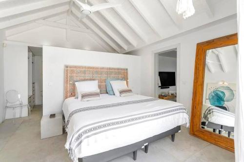 a white bedroom with a large bed and a mirror at Prestigious Villa & Apartment Marewa with Breathtaking Ocean View - Saint Martin French Side in Grand Case