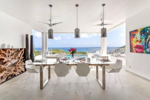 a dining room with a table and chairs and the ocean at Prestigious Villa & Apartment Marewa with Breathtaking Ocean View - Saint Martin French Side in Grand Case