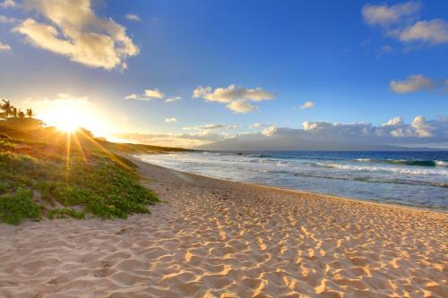 a sandy beach with the sun rising over the ocean at Hale Mahina B401 · HM B401 OceanFront 2BD Tropical Getaway in Kahana