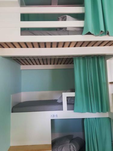 a bedroom with bunk beds with green curtains at Conde Surf Camp - Capsule Beds MIXED Dorm in Vila do Conde