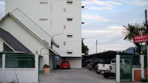 a white building with cars parked in a parking lot at ธรรศิกา อพาร์ทเม้นท์ in Kanchanaburi City