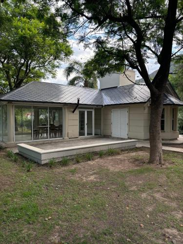 ein weißes Haus mit einem Baum davor in der Unterkunft casa quincho Puerta de la Quebrada in La Rioja