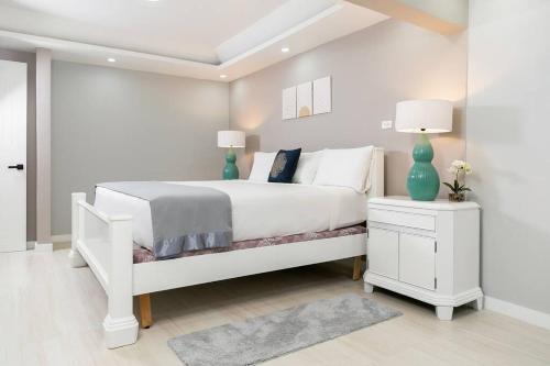 a white bedroom with a white bed and two lamps at Carter's Nest Villa - New Kingston - FIWI in Kingston