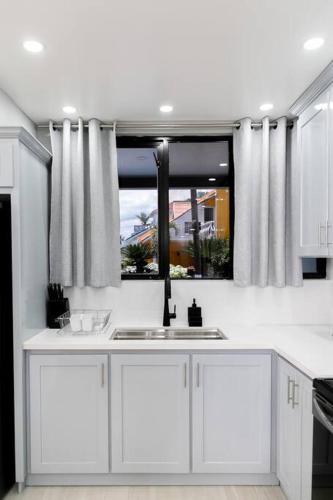 a white kitchen with a sink and a window at Carter's Nest Villa - New Kingston - FIWI in Kingston
