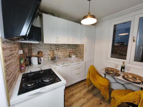 une cuisine avec des armoires blanches et une cuisinière dans l'établissement charmant appartement neuf et cosy, à Bondy