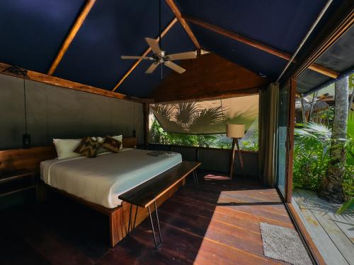 a bedroom with a bed and a ceiling fan at Libelula Tulum Beachfront Hotel in Tulum