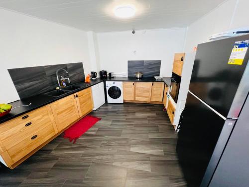 a kitchen with a black refrigerator and wooden cabinets at Tahiti Sunshine in Papeete