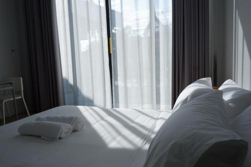 a bed with two towels on it in front of a window at สวัสดีซันไชน์กุดบาก in Sakon Nakhon