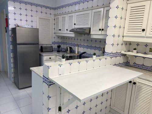 a kitchen with white cabinets and blue and white tiles at Apartamento Vista Mar in Praia da Vieira