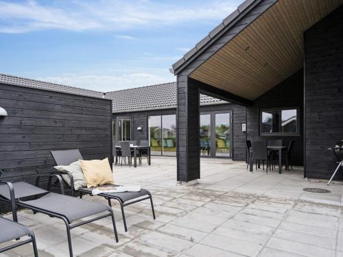an outdoor patio with chairs and tables and windows at 5 star holiday home in Nørre Nebel in Nørre Nebel