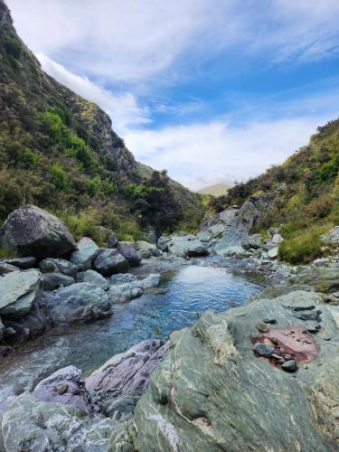 a river with rocks and a mountain in the background at Danseys Pass Lavender Farm Retreat in Livingstone