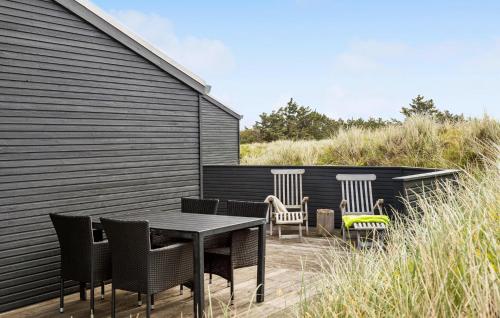 a patio with a table and chairs and a wall at Awesome Home In Løkken With Kitchen in Løkken