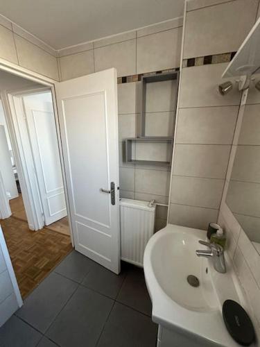 La salle de bains est pourvue d'un lavabo blanc et d'une porte. dans l'établissement Appartement 4 chambres Villejuif, à Villejuif