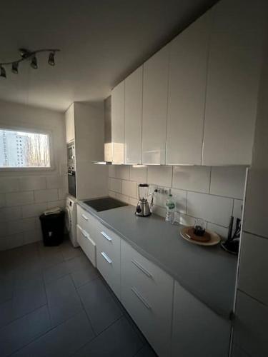 une cuisine avec des armoires blanches et un comptoir dans l'établissement Appartement 4 chambres Villejuif, à Villejuif