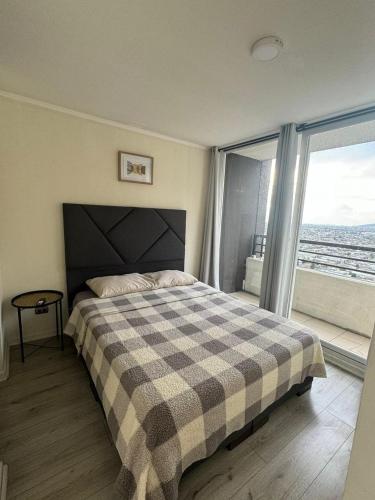 a bedroom with a bed with a plaid blanket and a window at Depasfs in Santiago