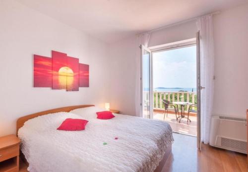 a bedroom with a bed with red pillows and a balcony at Apartments and rooms with parking space Plat, Dubrovnik - 23567 in Mlini