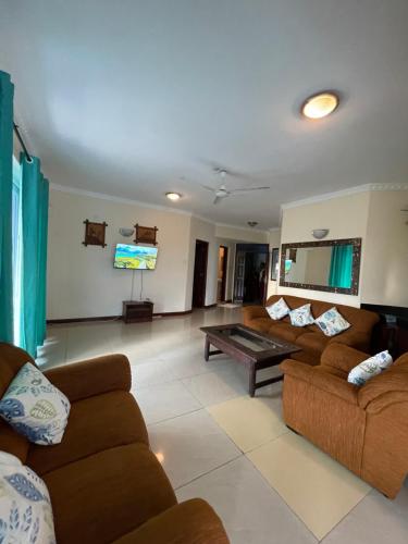 ein Wohnzimmer mit Sofas und einem Flachbildfernseher in der Unterkunft Sunrise Resort Apartments in Mombasa