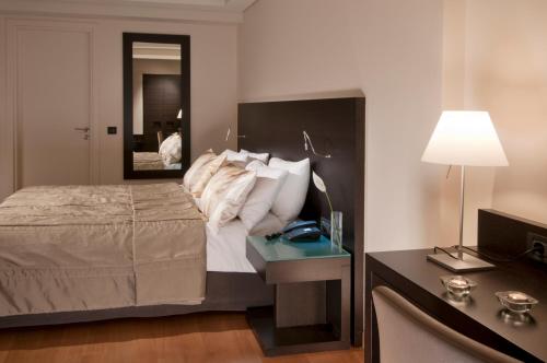 a bedroom with a bed and a table with a lamp at O&B Athens Boutique Hotel in Athens