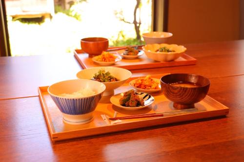 ein Tablett mit Schüsseln mit Essen auf einem Holztisch in der Unterkunft Yanagawa B&B hatago in Yanagawa