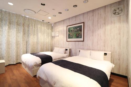a hotel room with two beds and a window at Ideal Momodani イデアール桃谷 in Osaka