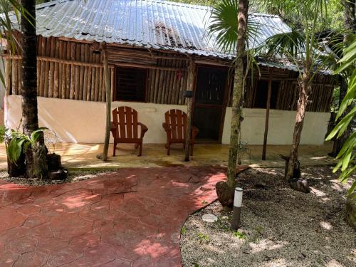a house with two chairs and palm trees in front of it at Cabañas Jardin del Amor in Tulum